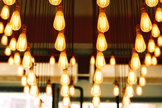 Etliche Glühbirnen bzw. moderne LED-Deckenleuchten in Reih und Glied geben warmes Licht